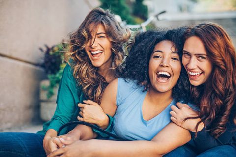 Three young women laughing outdoors